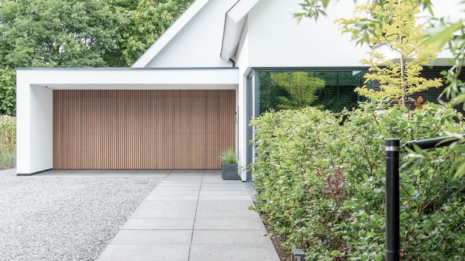 De Afrormosia houten garagedeuren en voordeur passen perfect in de strakke gevel van de woning