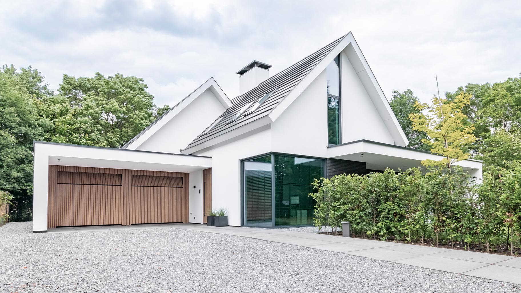 De Afrormosia houten garagedeuren en voordeur passen perfect in de strakke gevel van de woning