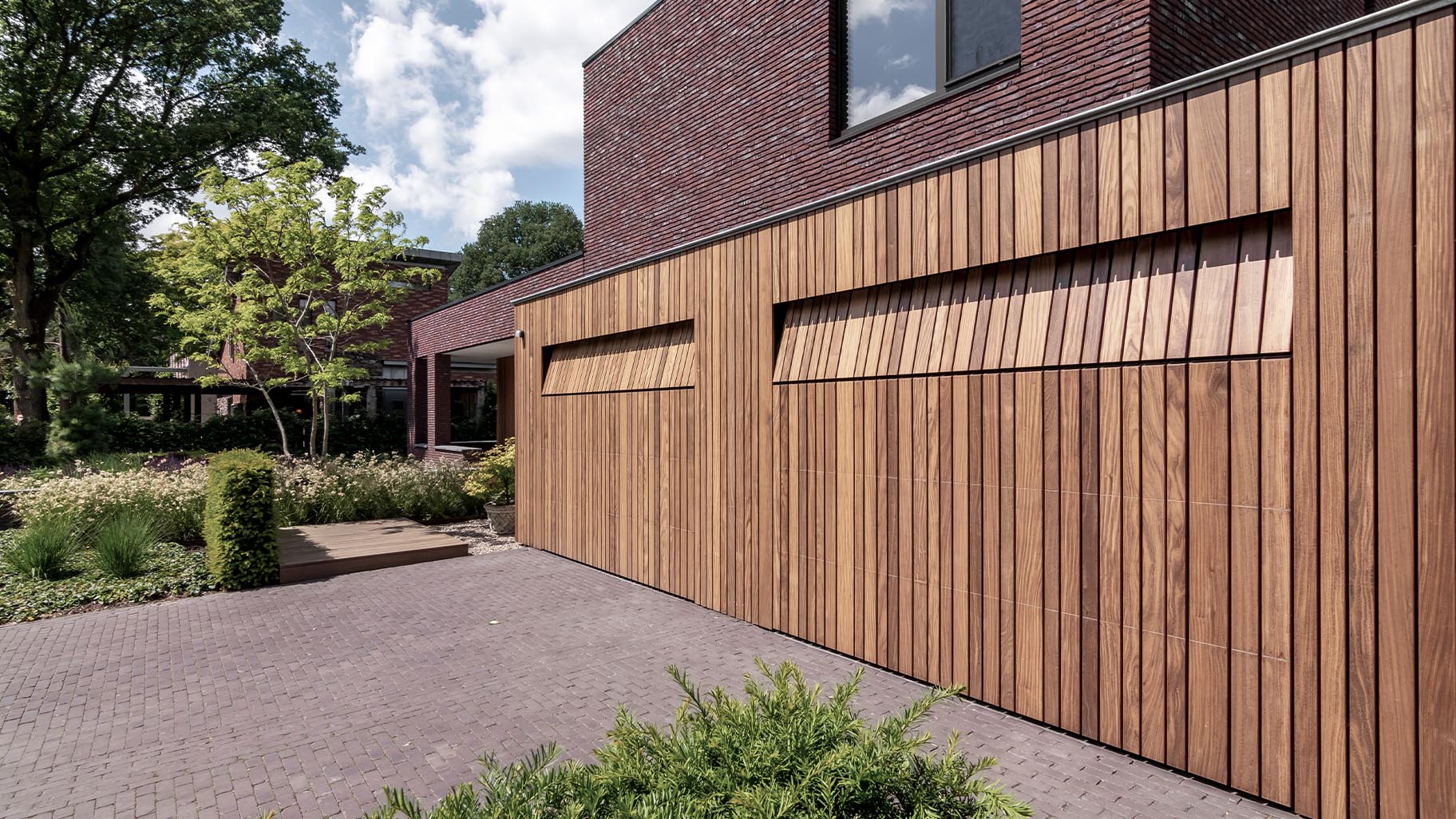 Moderne woning met dubbele houten sectionaaldeuren die bijdragen aan een stijlvolle uitstraling