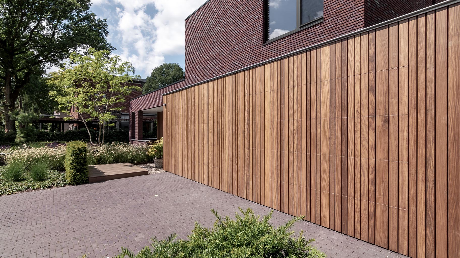 De houten garagedeuren zijn onopvallend ingebouwd in het ontwerp van de gevelbekleding