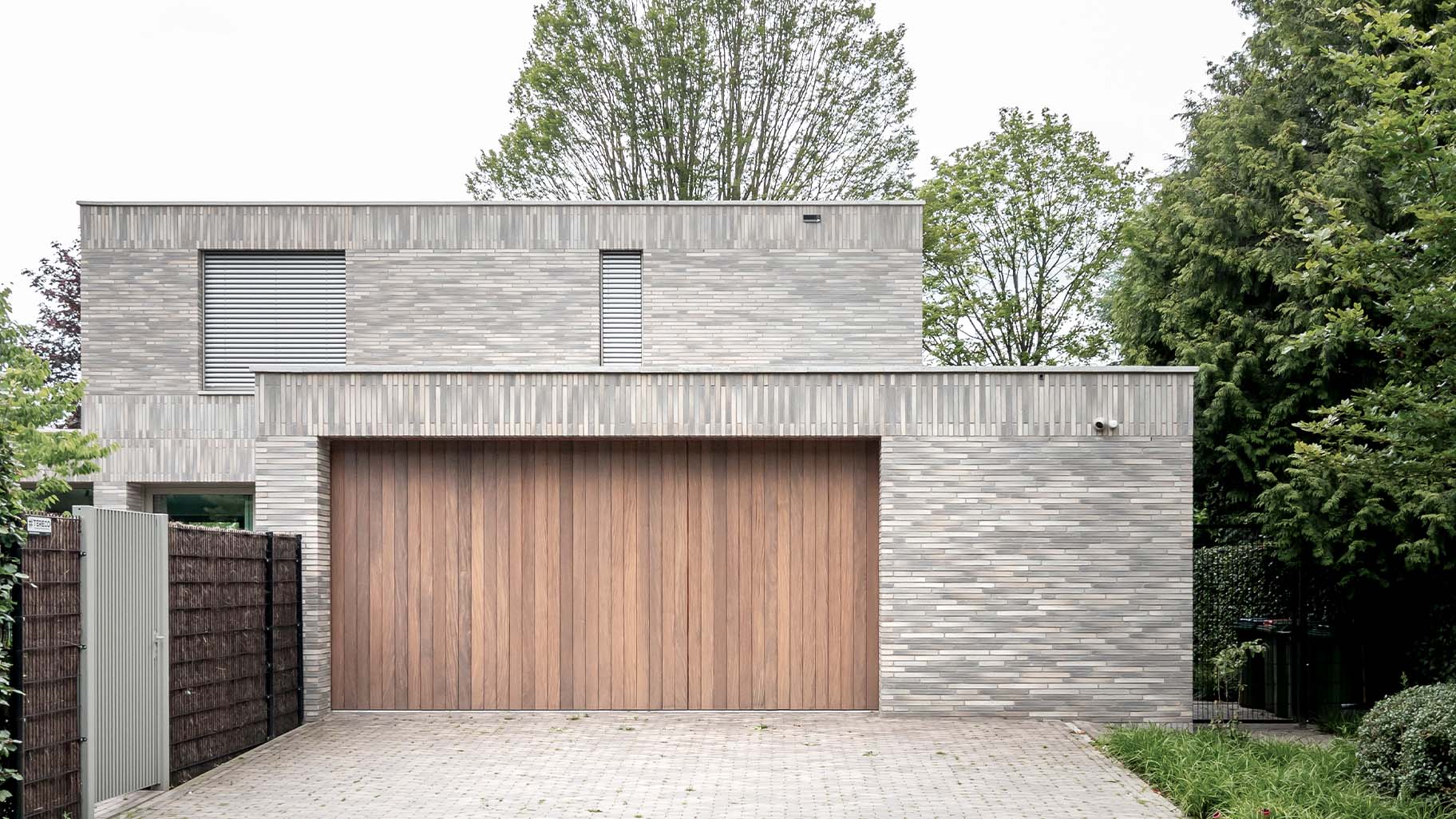 Dubbele zijwaartse garagedeuren van Different Doors, met een luxe uitstraling van Afrormosia hout, ontworpen voor deze moderne villa