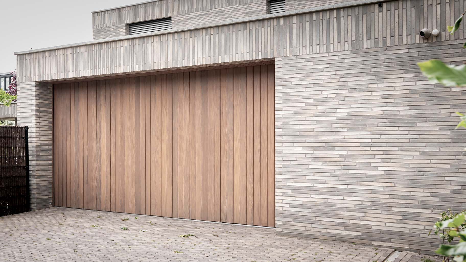 Dubbele zijwaartse garagedeuren van Different Doors, met een luxe uitstraling van Afrormosia hout, ontworpen voor deze moderne villa