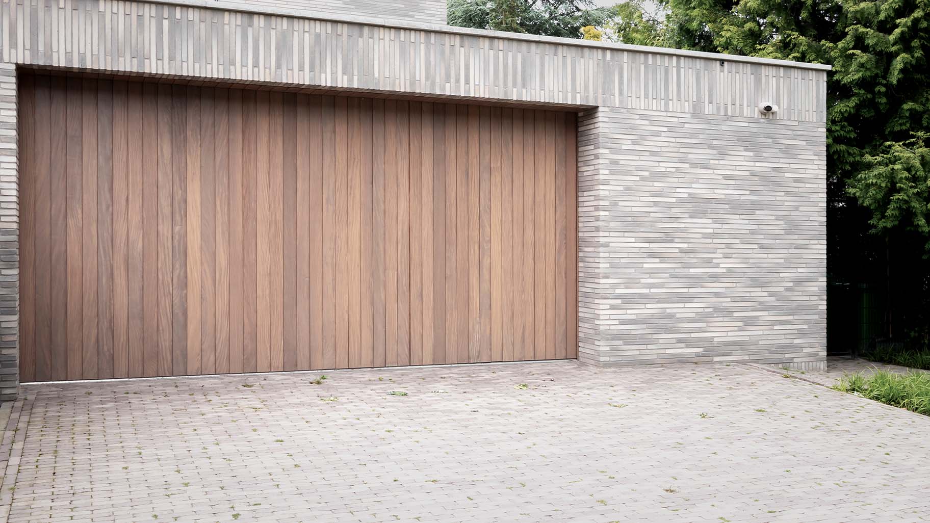 Moderne nieuwbouwvilla met dubbele zijwaartse houten garagedeuren onzichtbaar verwerkt in de gevel