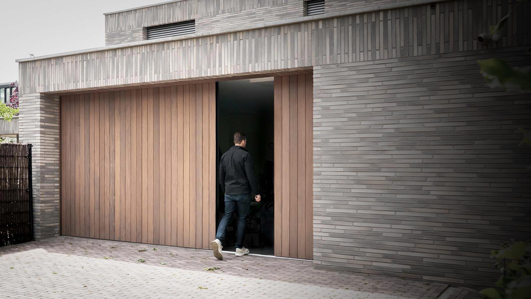 De houten garagedeuren openen zijwaarts en passen perfect in de houten gevelbekleding van de villa