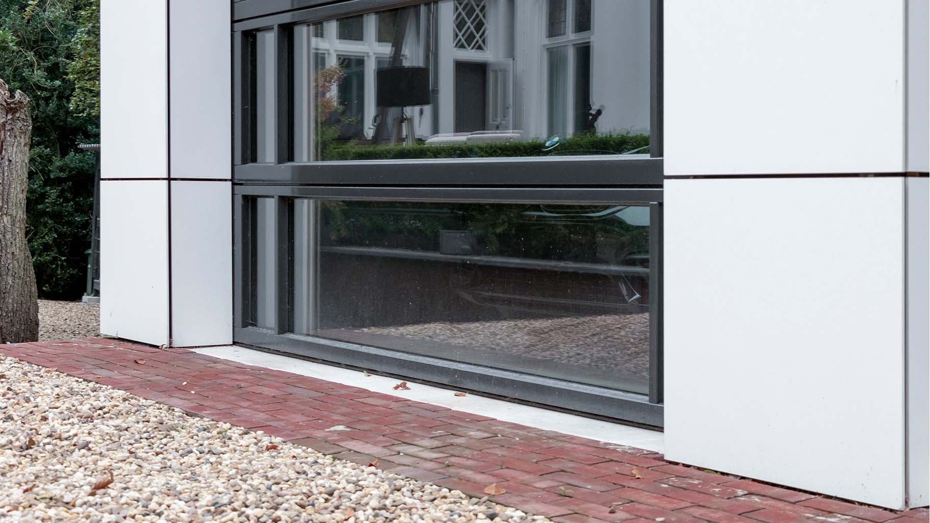 Detail van glazen garagedeur met houten frame, helder glas en strakke lijnen