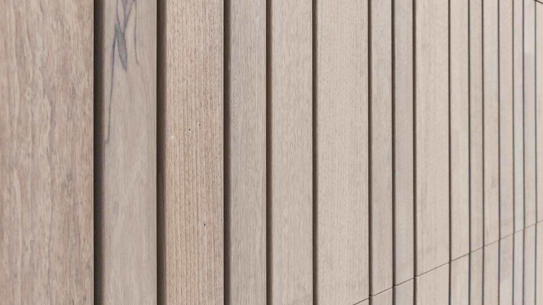 Close-up van fraké houten garagedeur met zichtbare houtnerf en warme tinten