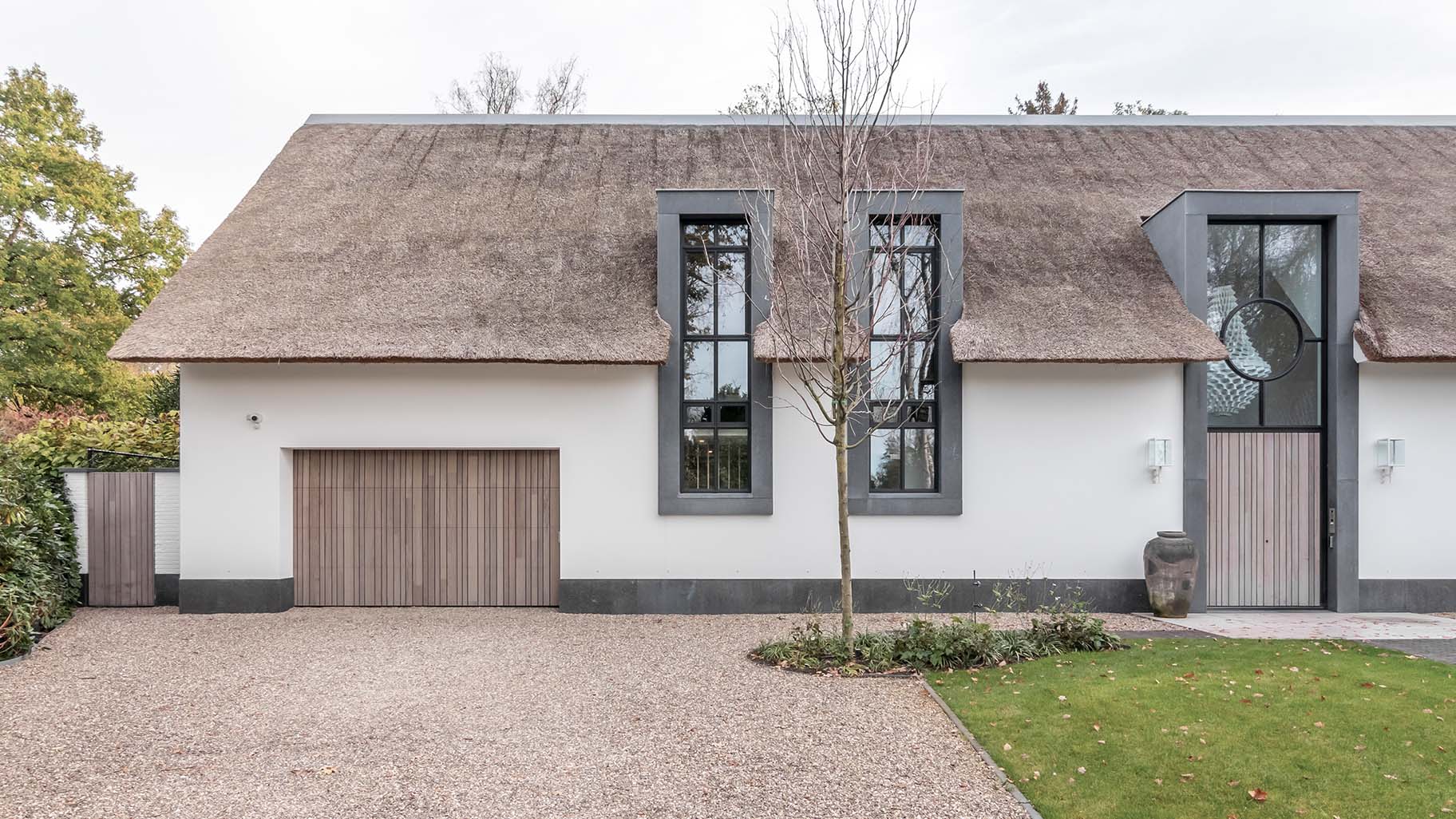 Landelijke woning met rieten dak en houten garagedeur achter de dag voor een harmonieuze uitstraling