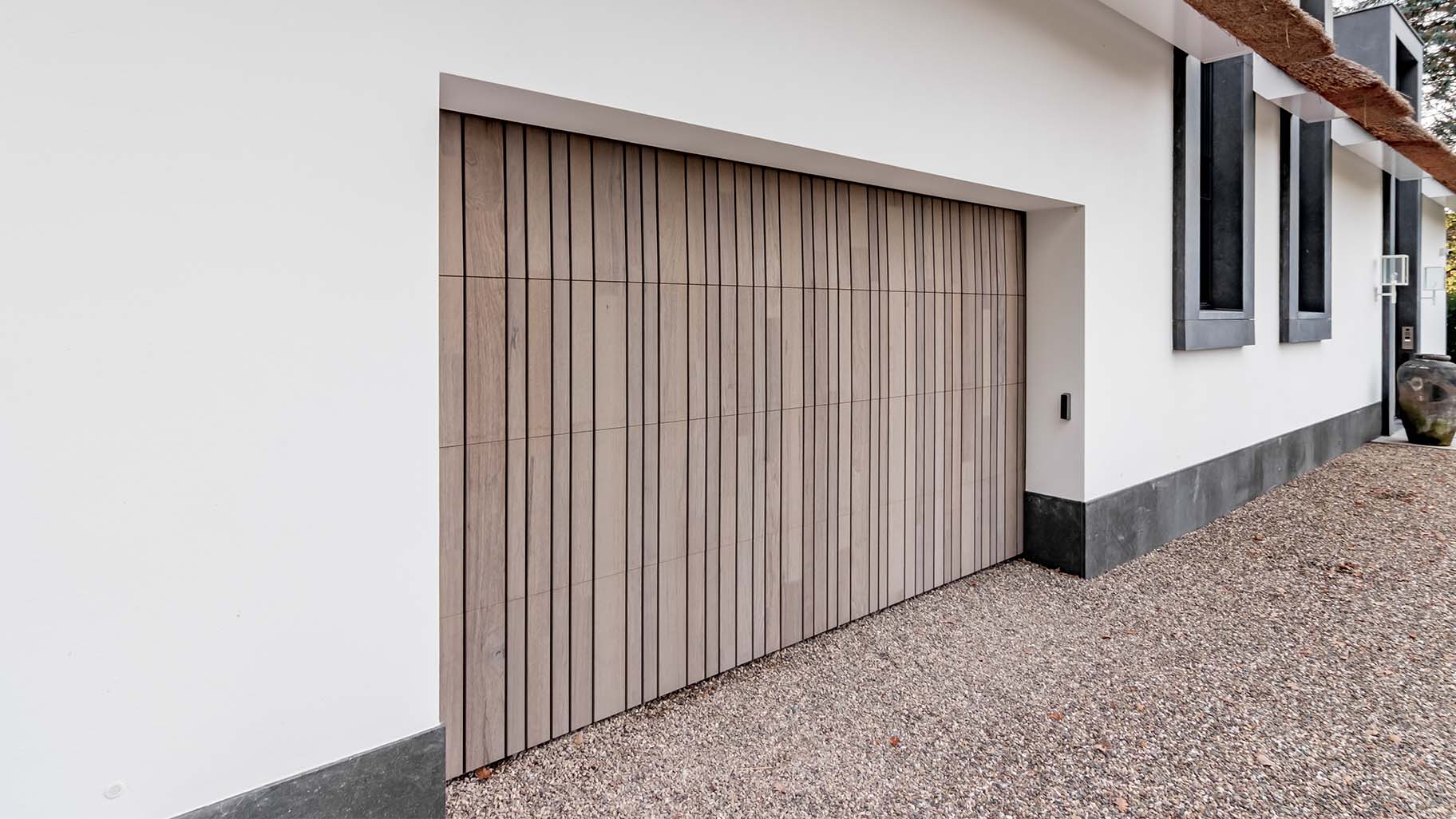 Landelijke woning met rieten dak en houten garagedeur achter de dag voor een harmonieuze uitstraling