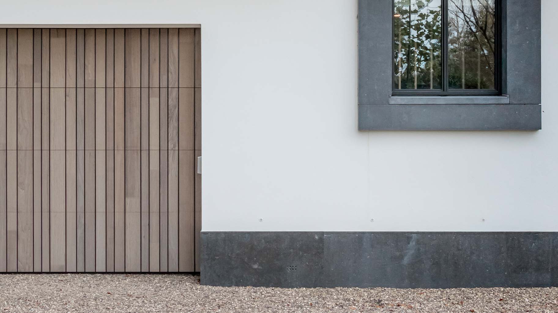 Different Doors houten garagedeur achter de dag, passend bij landelijke woning met rieten dak