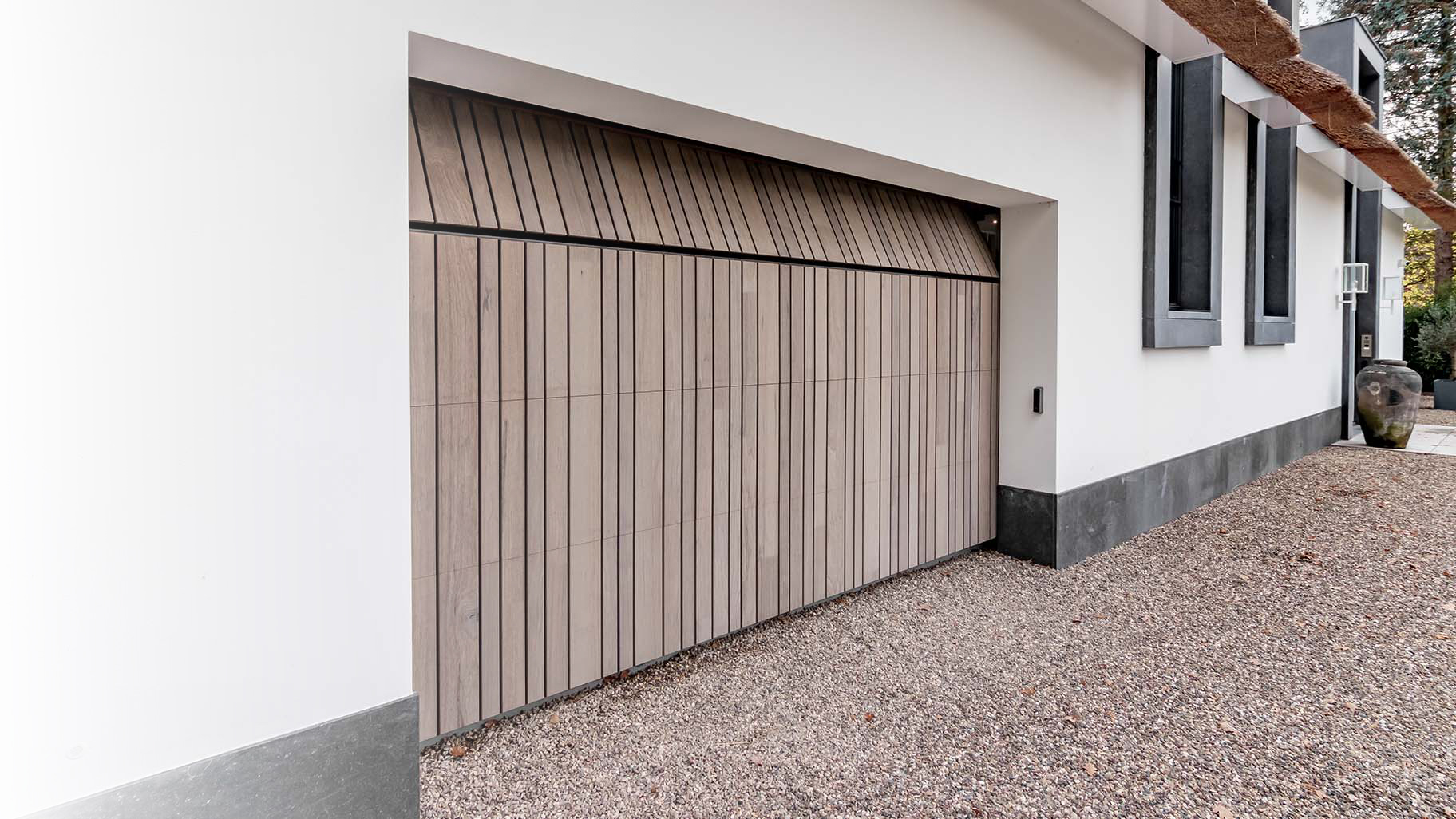 Landelijke woning met rieten dak en houten garagedeur achter de dag voor een harmonieuze uitstraling