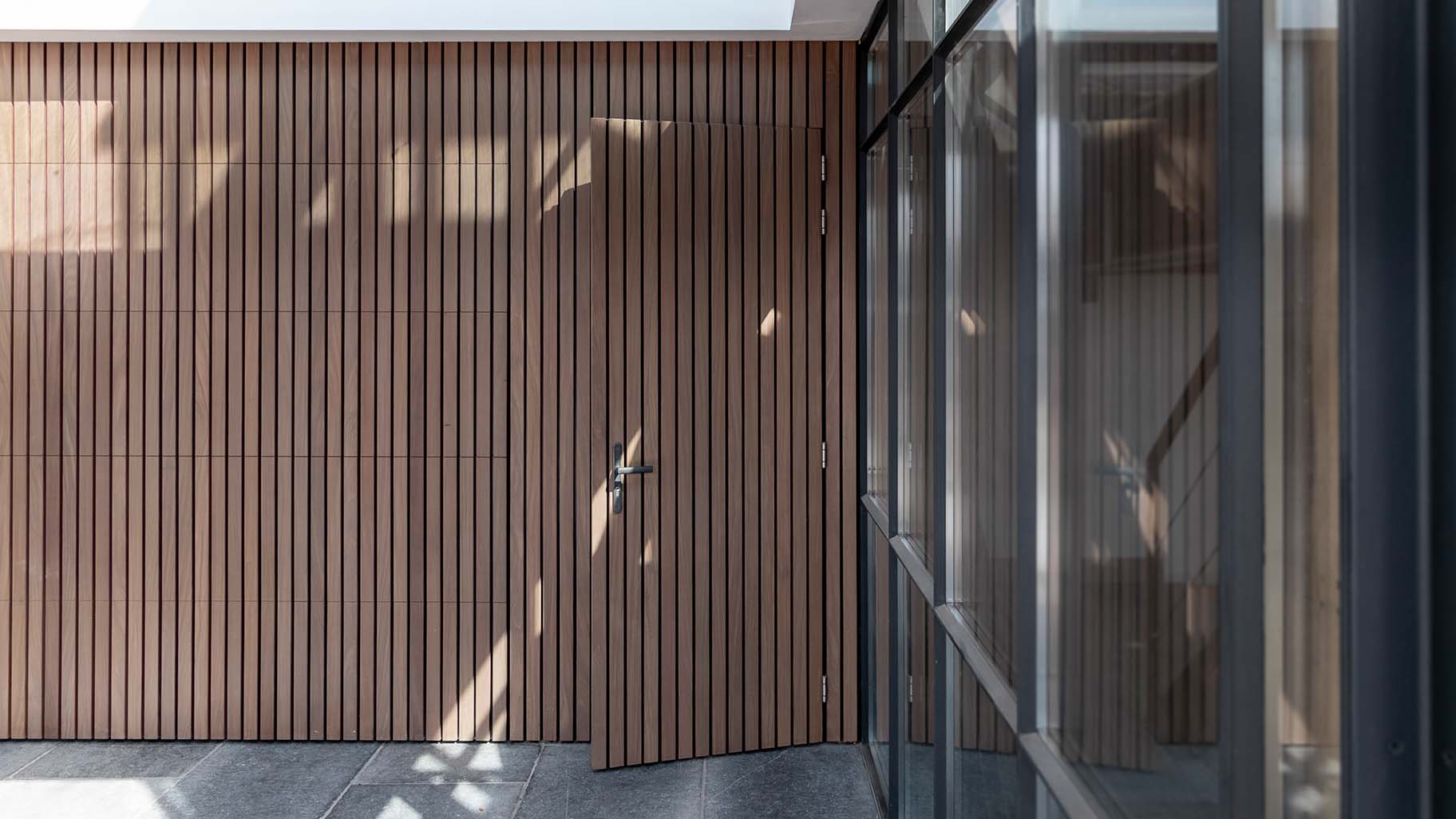 Different Doors Afrormosia houten garagedeur met verticale latten en loopdeur