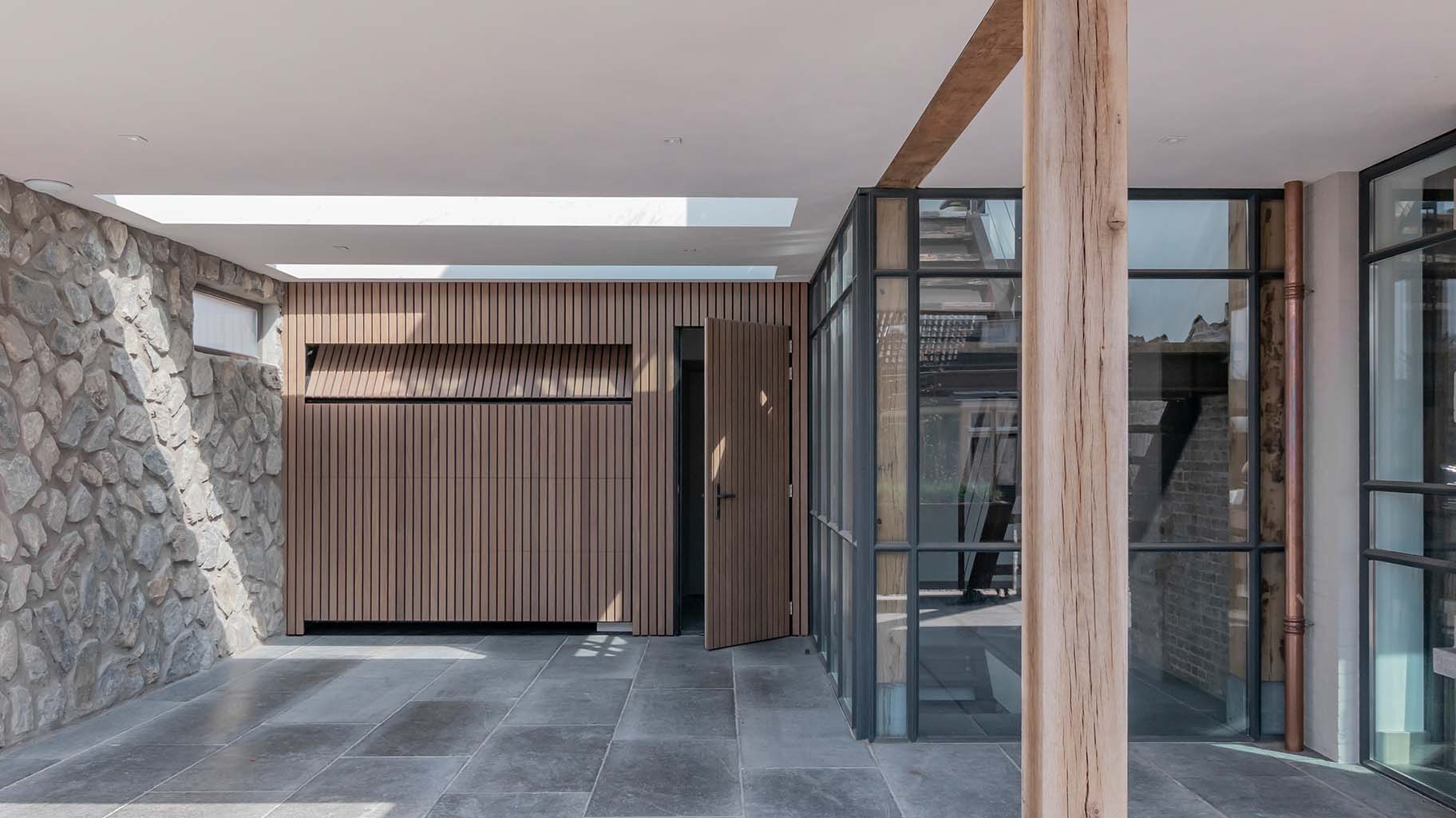 Moderne woning met Afrormosia houten garagedeur en loopdeur, passend bij de gevel