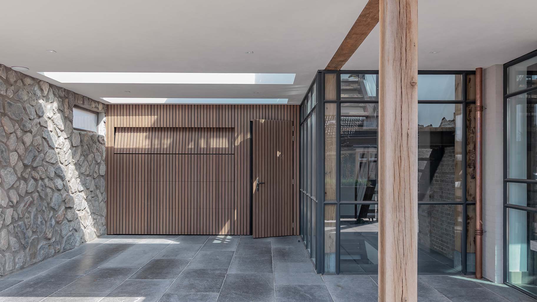 Moderne woning met Afrormosia houten garagedeur en loopdeur, passend bij de gevel