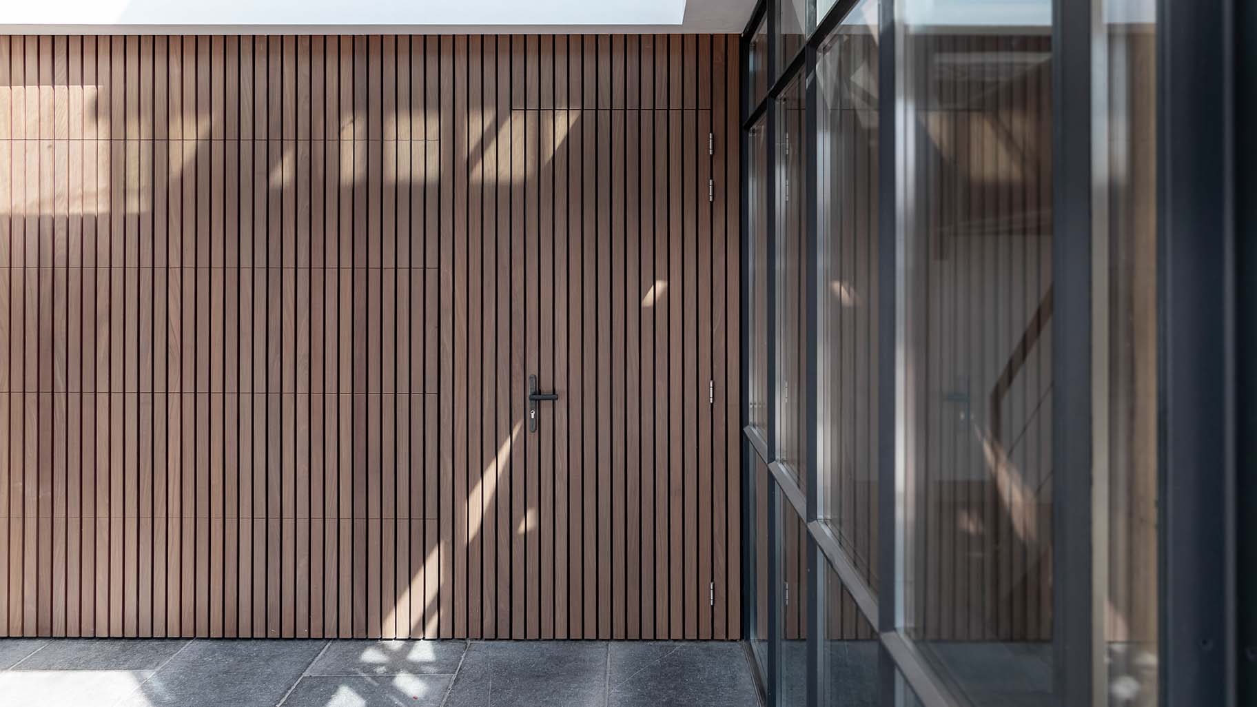 Different Doors Afrormosia houten garagedeur met verticale latten en loopdeur