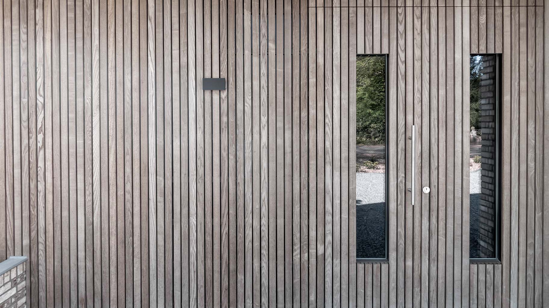 Onzichtbare houten garagedeur geïntegreerd in de gevel, gerealiseerd door Different Doors