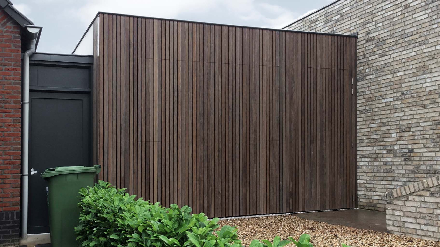 Verticale plato garagedeur gelijk in de gevel met loopdeur - Different Doors
