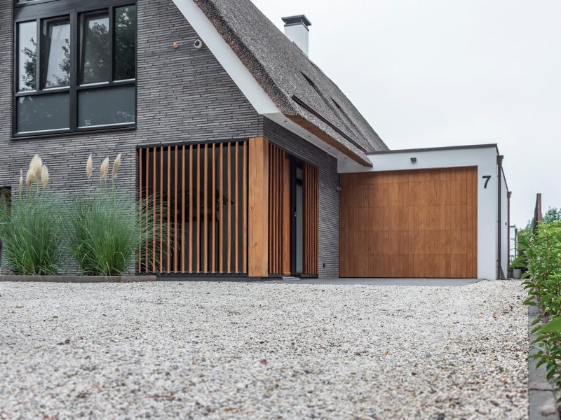 Moderne landelijke villa met een eikenhouten garagedeur, voordeur en gevelbekleding