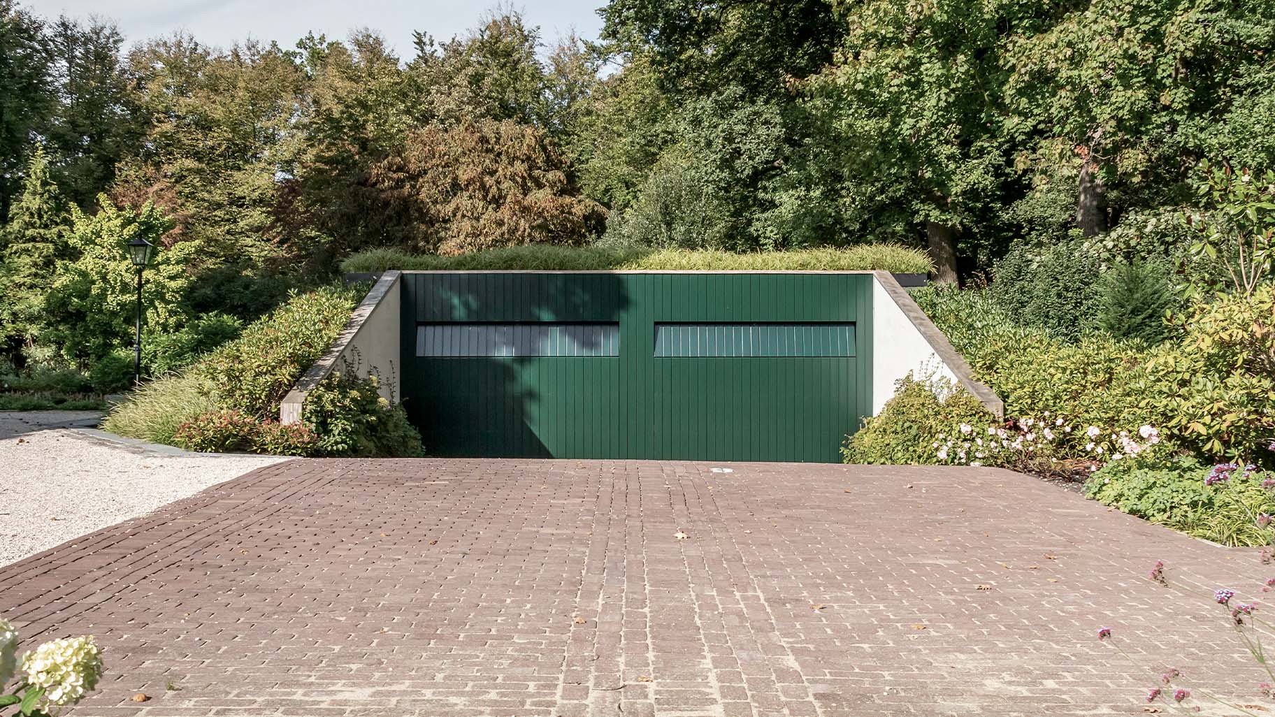 Unieke garage met twee houten sectionaaldeuren in diepgroene kleur