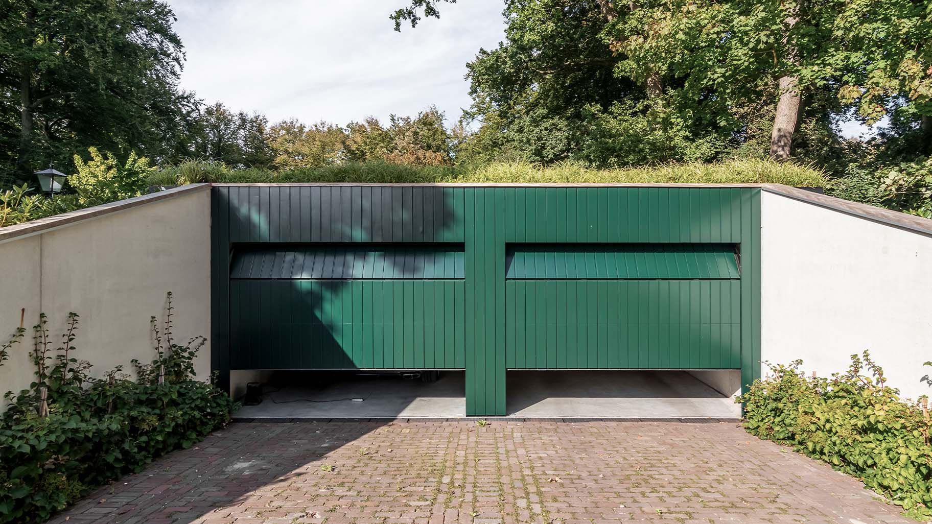 Unieke garage met twee houten sectionaaldeuren in diepgroene kleur