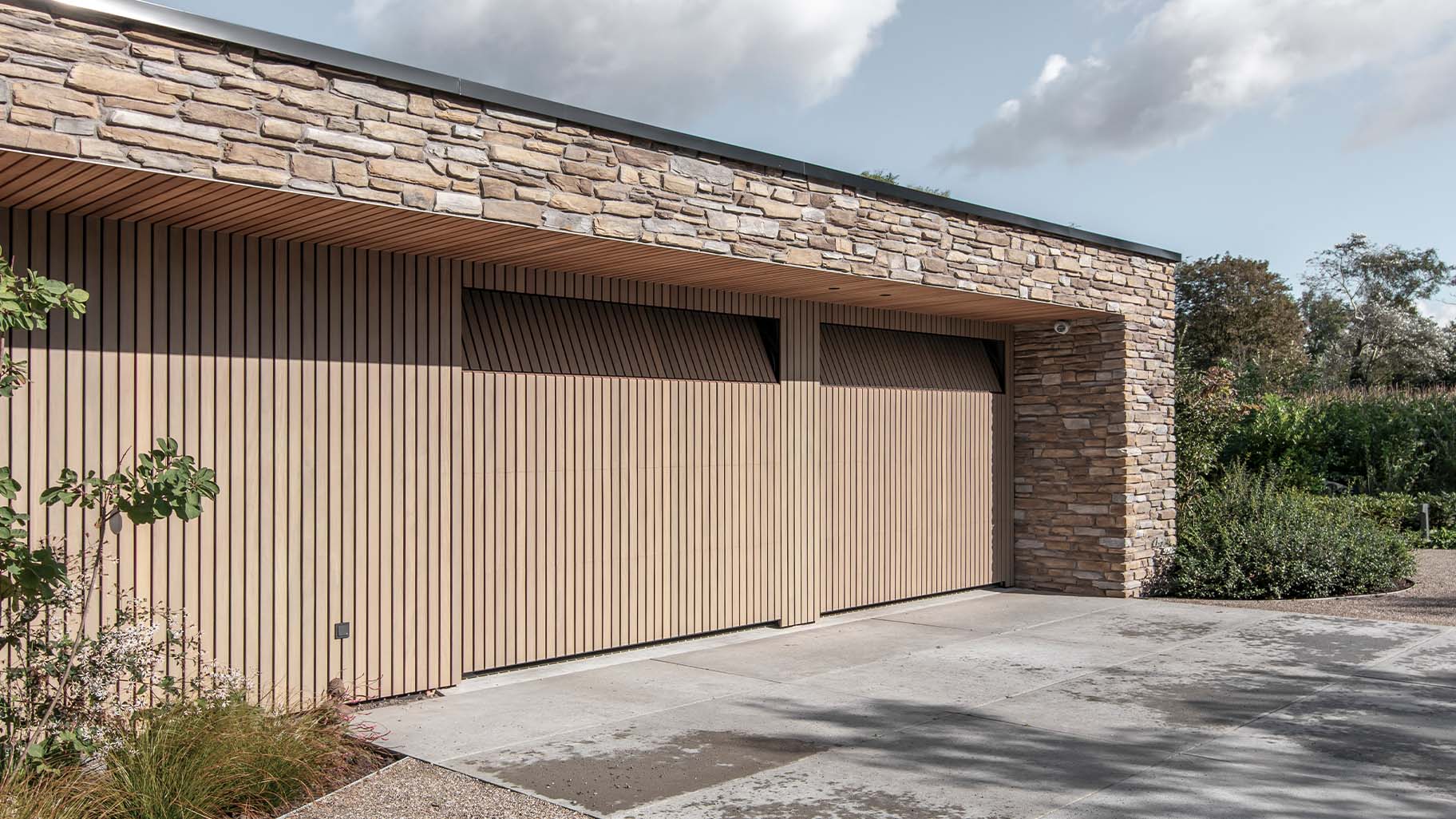 Moderne nieuwbouwwoning met twee houten sectionaaldeuren van Afrormosia hout