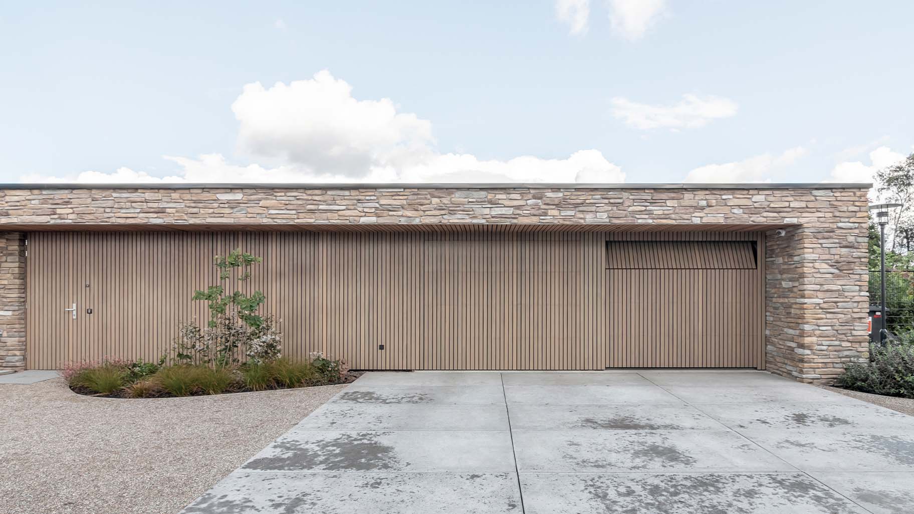 Moderne nieuwbouwwoning met twee houten sectionaaldeuren van Afrormosia hout
