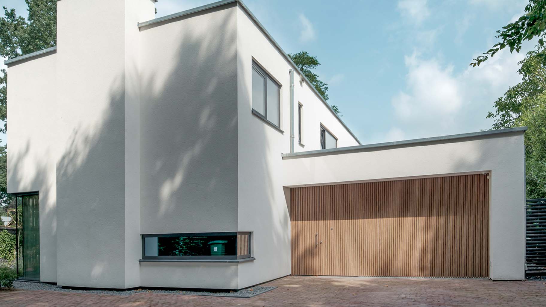 Moderne villa met Afrormosia houten zijwaartse sectionaaldeur en bijpassende voordeur