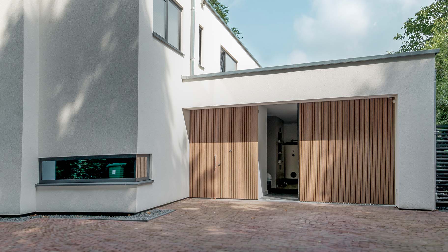 Moderne villa met Afrormosia houten zijwaartse sectionaaldeur en bijpassende voordeur