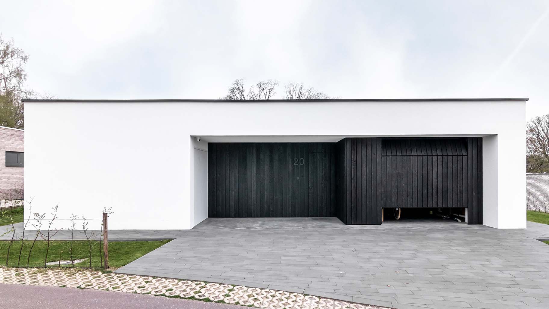 Strakke gevel met zwarte Shou Sugi Ban houten deuren, passend bij de minimalistische woning