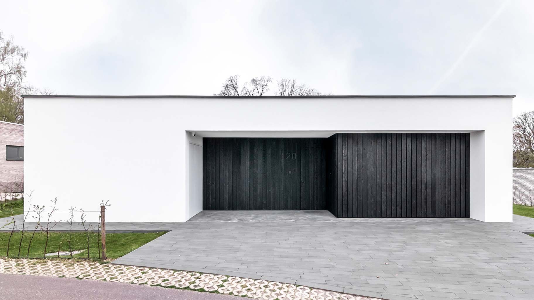 Strakke gevel met zwarte Shou Sugi Ban houten deuren, passend bij de minimalistische woning