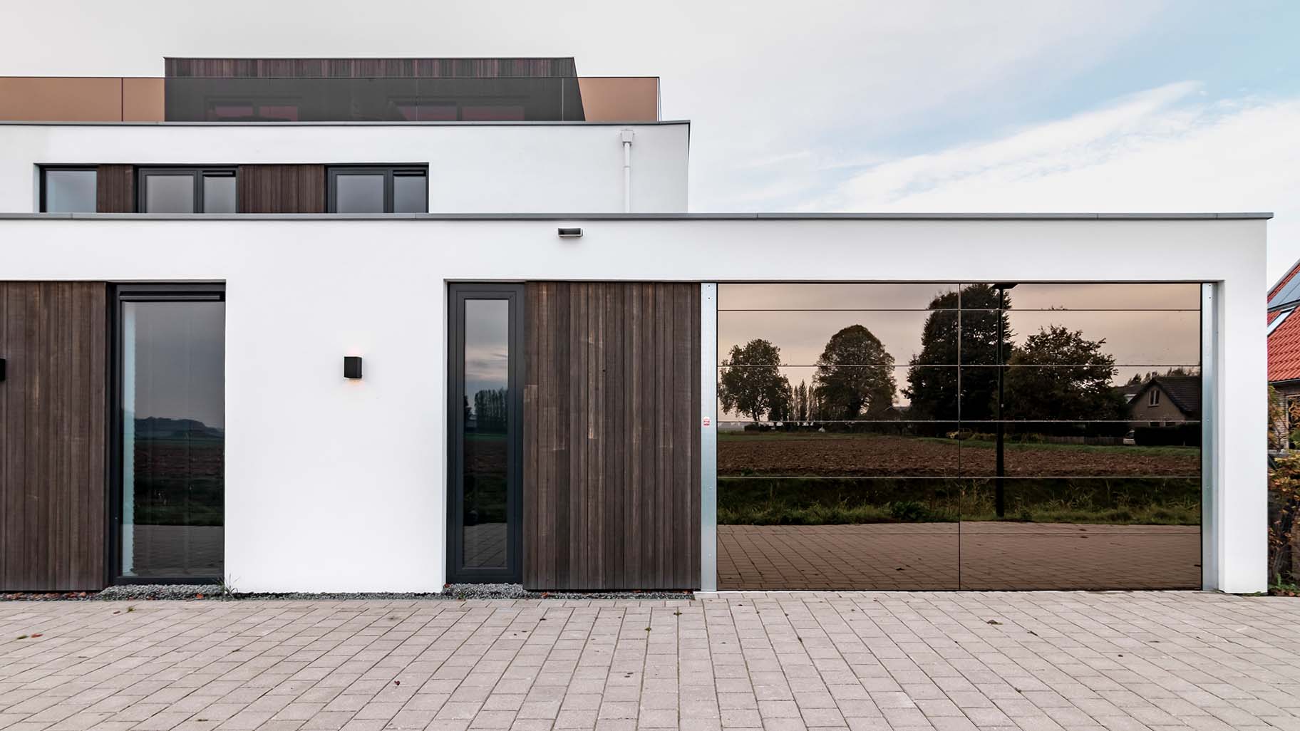 Moderne woning met een unieke garagedeur met spiegelwand geplaatst door Different Doors