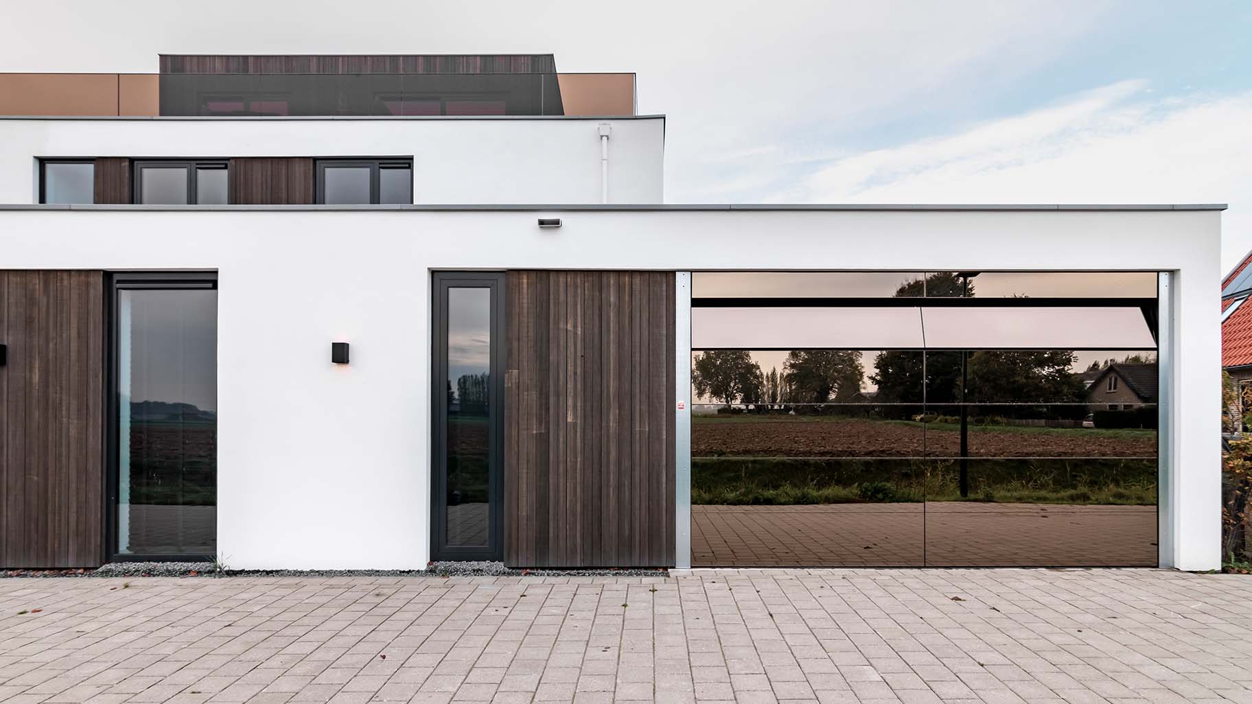 Moderne woning met een unieke garagedeur met spiegelwand geplaatst door Different Doors