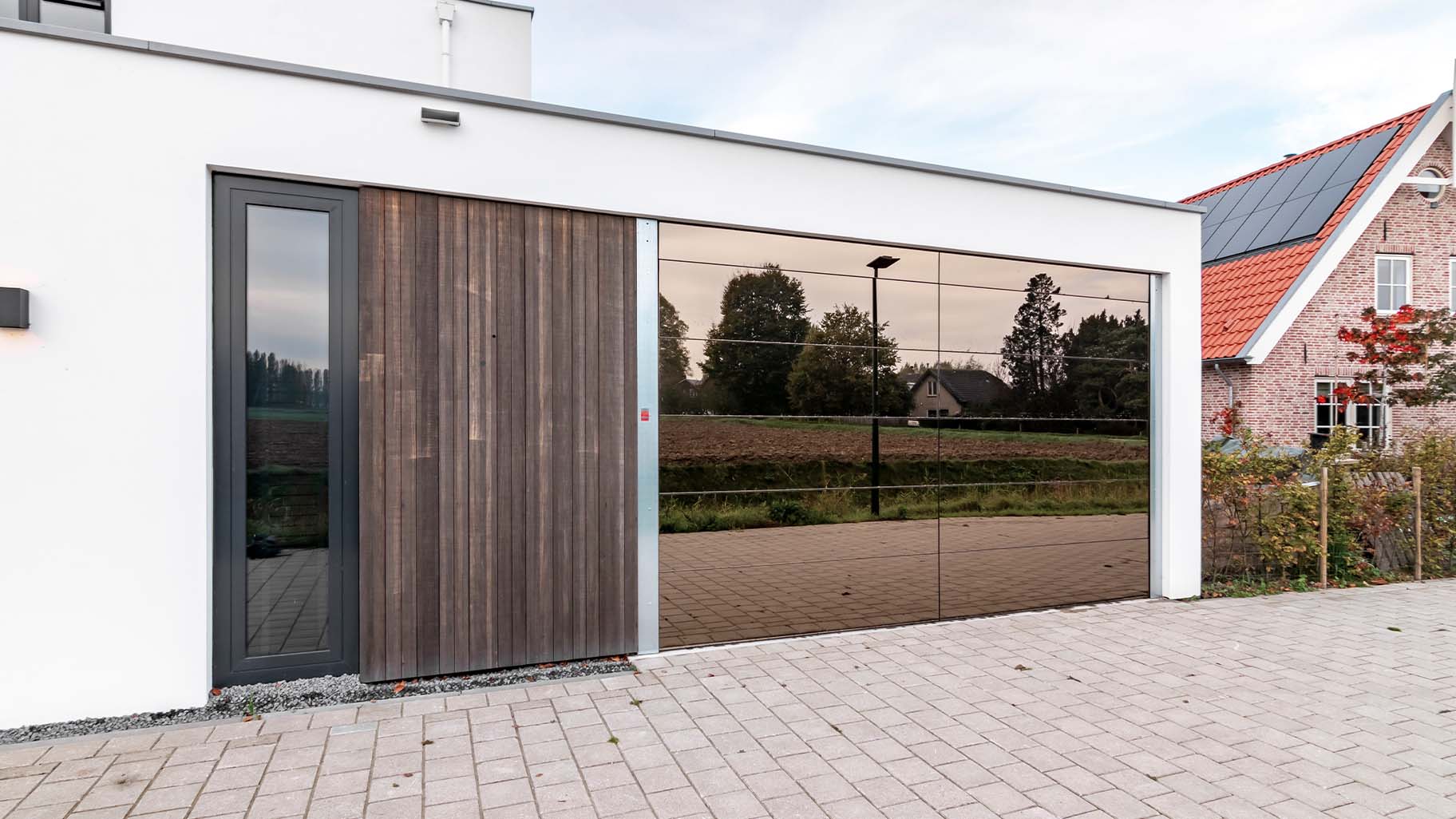 Moderne woning met een unieke garagedeur met spiegelwand geplaatst door Different Doors