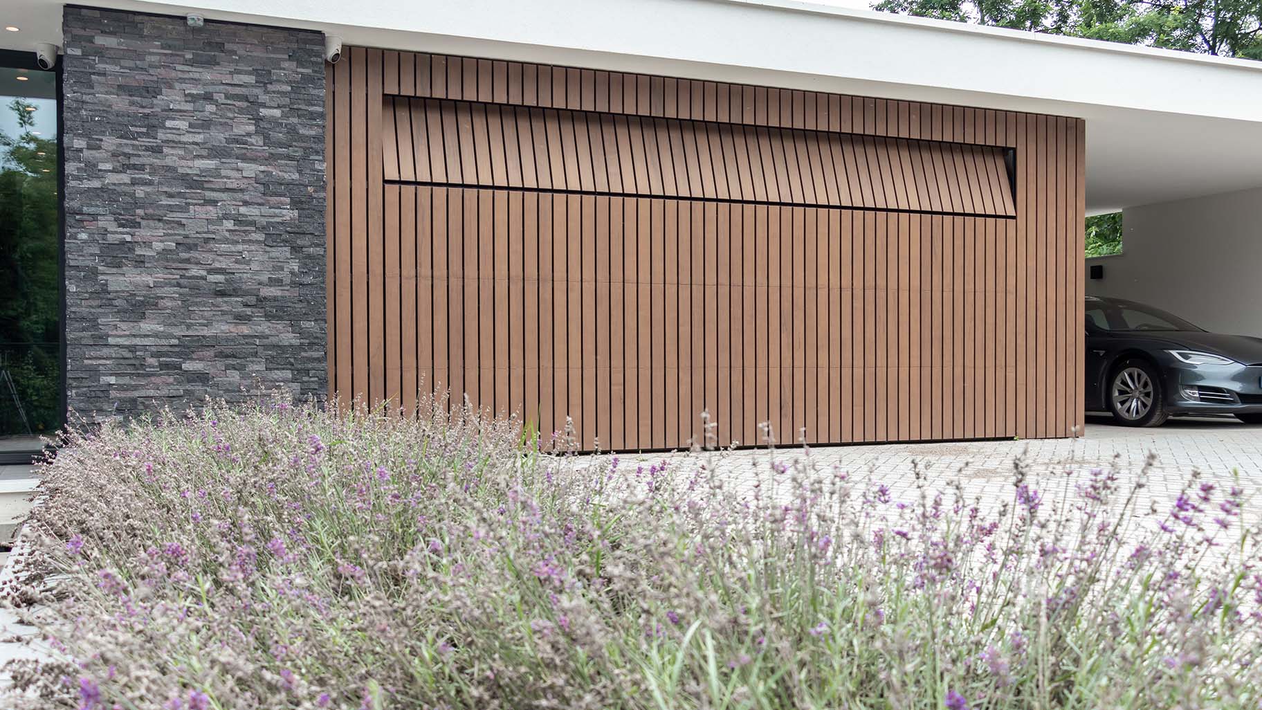 houten sectionaaldeur met verticale latten in warme bruintinten, passend bij de gevelbekleding