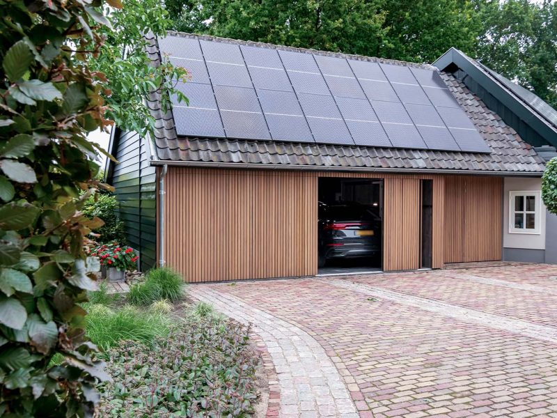 Gevelrenovatie van boerderij met een nieuwe zijwaartse houten garagedeur met dunne latjes