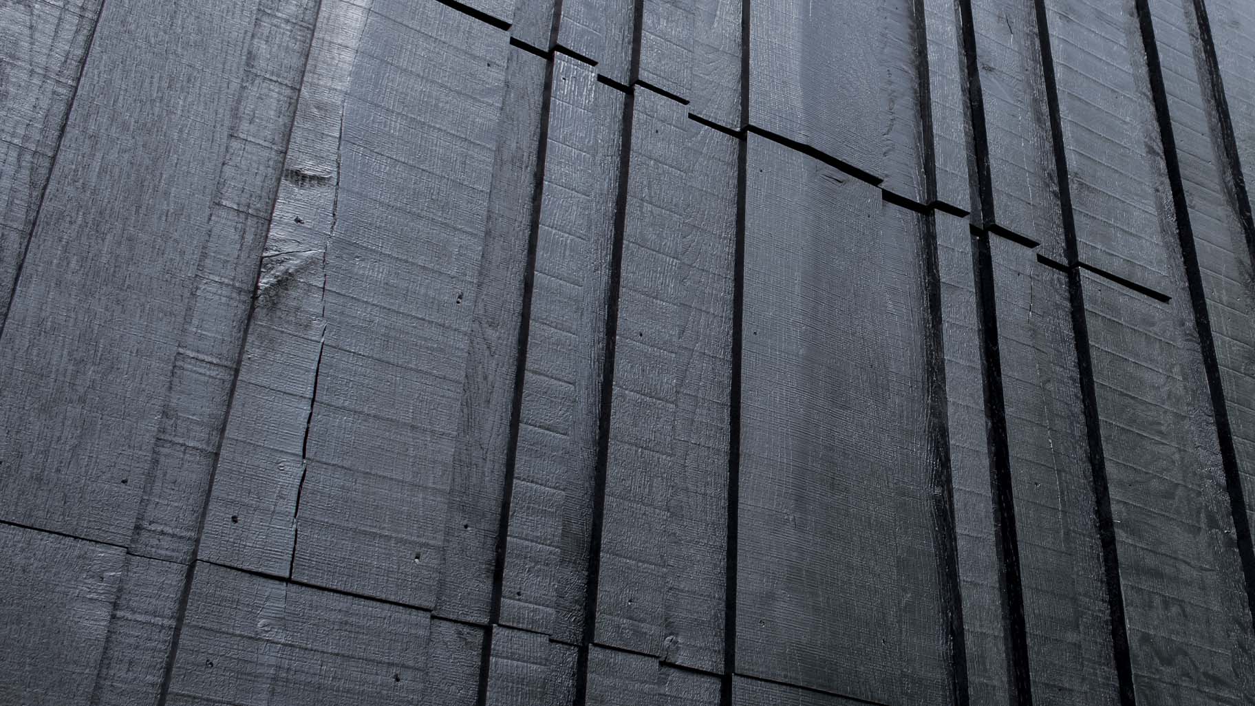 Close-up van zwarte houten garagedeur met variërende breedtes in verticale latten