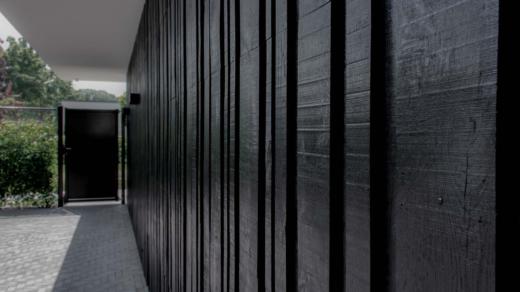 Close-up van zwarte houten garagedeur met variërende breedtes in verticale latten
