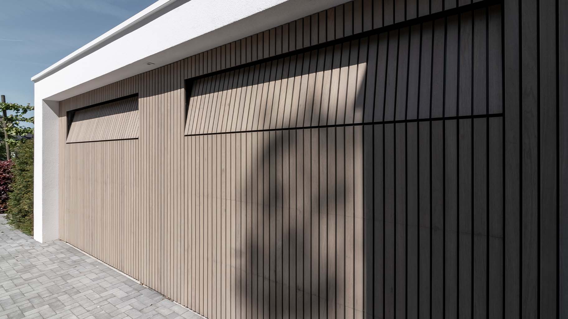 Frake houten garagedeuren bij moderne villa met gevelbekleding