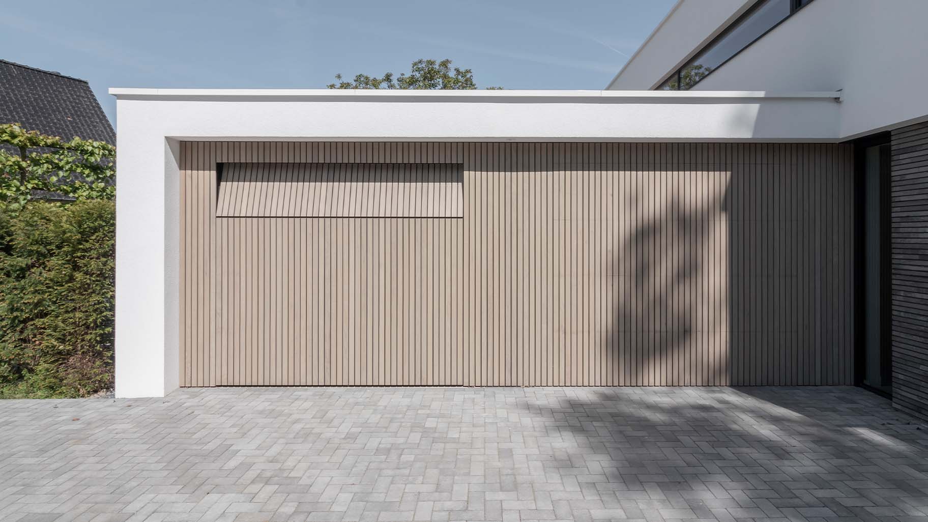 Frake houten garagedeuren bij moderne villa met gevelbekleding