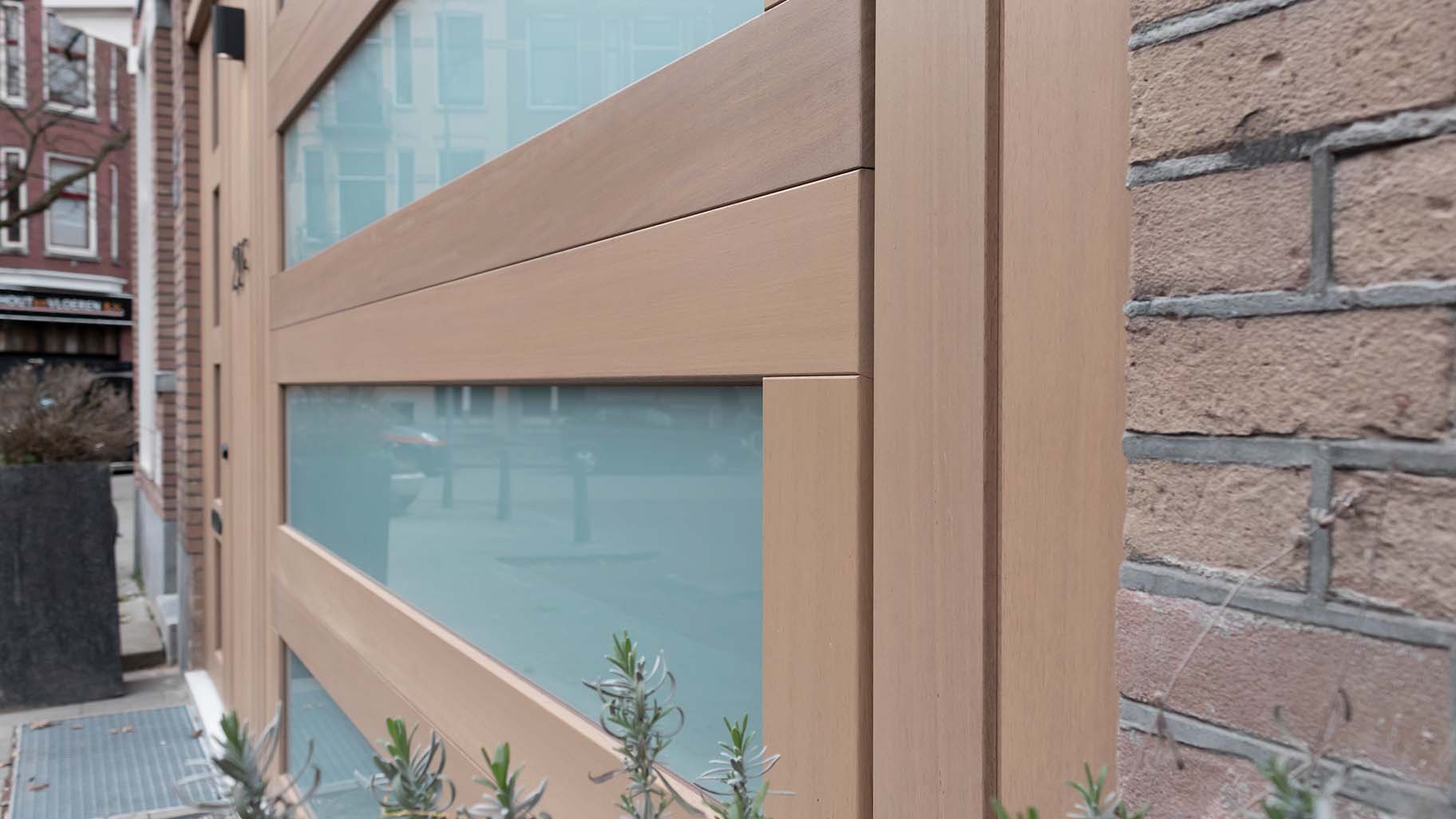 Houten garagedeur met voordeur in Iroko hout en melkglas gelijk in de gevel